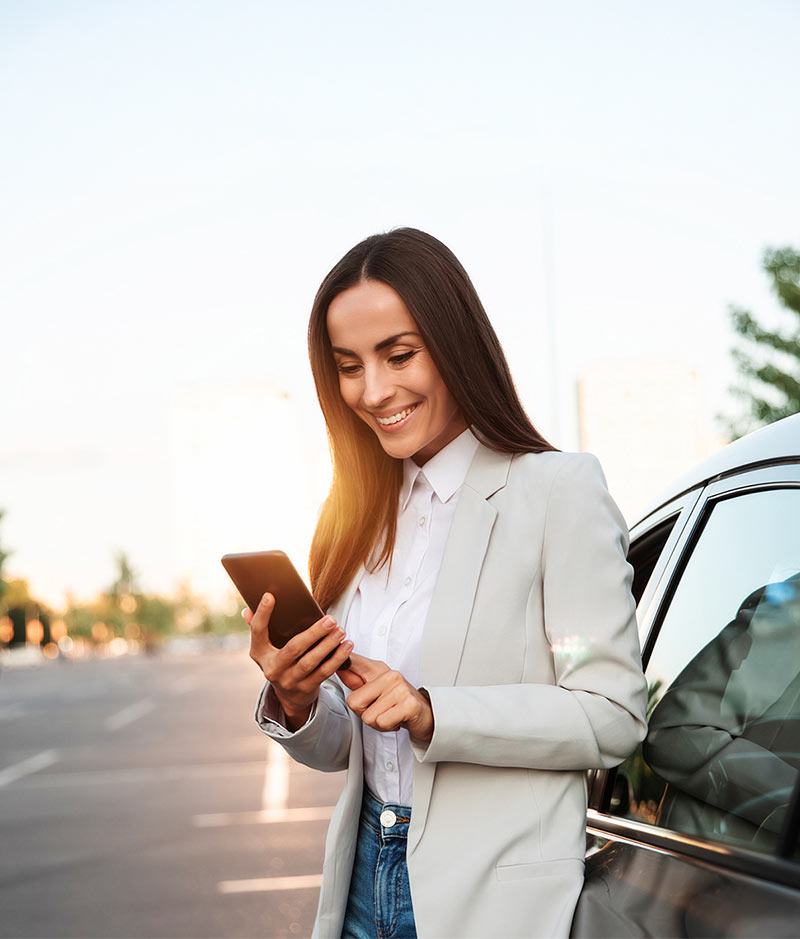 woman on phone next to car calling collision repair shop