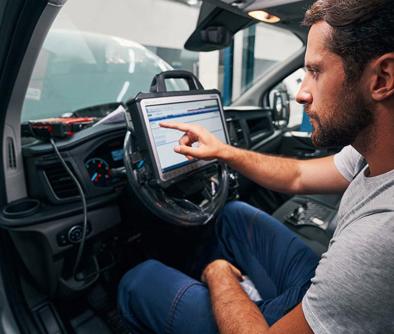 certified technician at Mills Collision Center shop scanning vehicle after repair